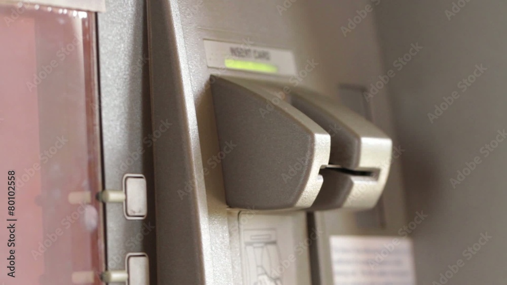 Detail of a woman's hand inserting and removing a bank card at an ATM.