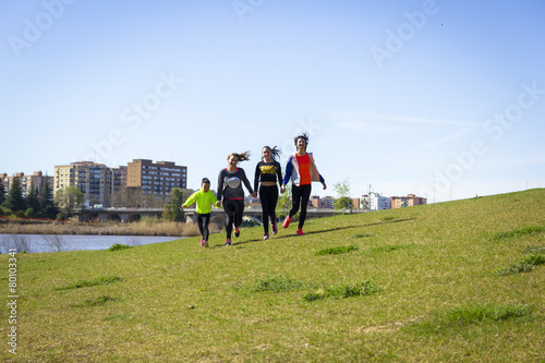 Cuatro chicas jóvenes haciendo ejercicio junto al río © Trepalio