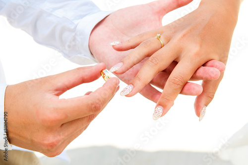 Groom giving an engagement ring to his bride under the arch deco