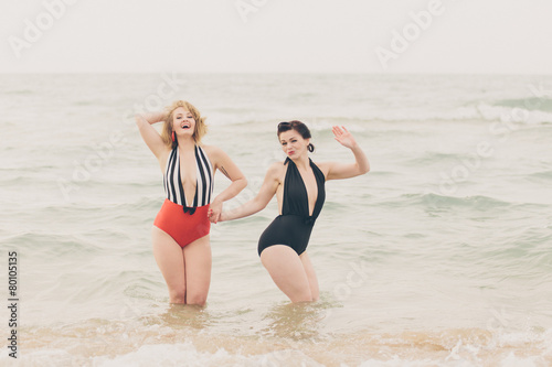 Two Beautiful Young Women in Retro Vintage Swimsuits at Beach