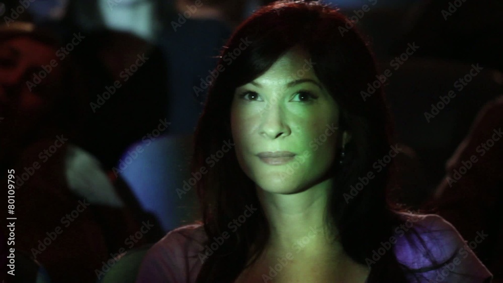 Two young women comment to each other while watching a movie. Camera is jib-mounted and moving images are projected on the people. Two young women comment to each other while watching a movie. Camera is jib-mounted and moving images are projected on the people.