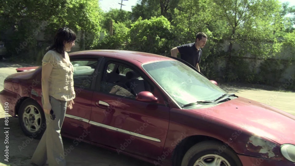 Couple get out of car and argue about who is to blame for an accident that damaged the car. Man sends woman away to avoid further confrontation. Couple get out of car and argue about who is to blame for an accident that damaged the car. Man sends woman away to avoid further confrontation.