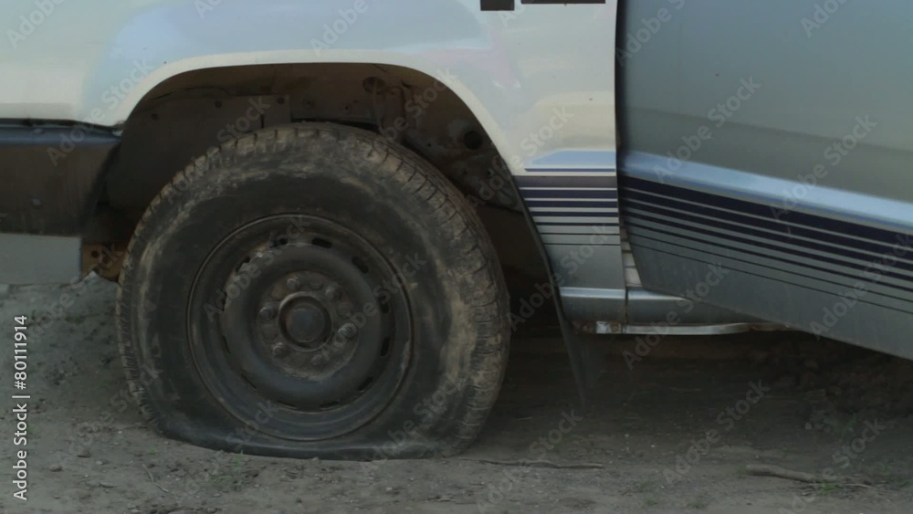 Driver discovers he has a flat tire, gets out of his truck and calls for roadside assistance.