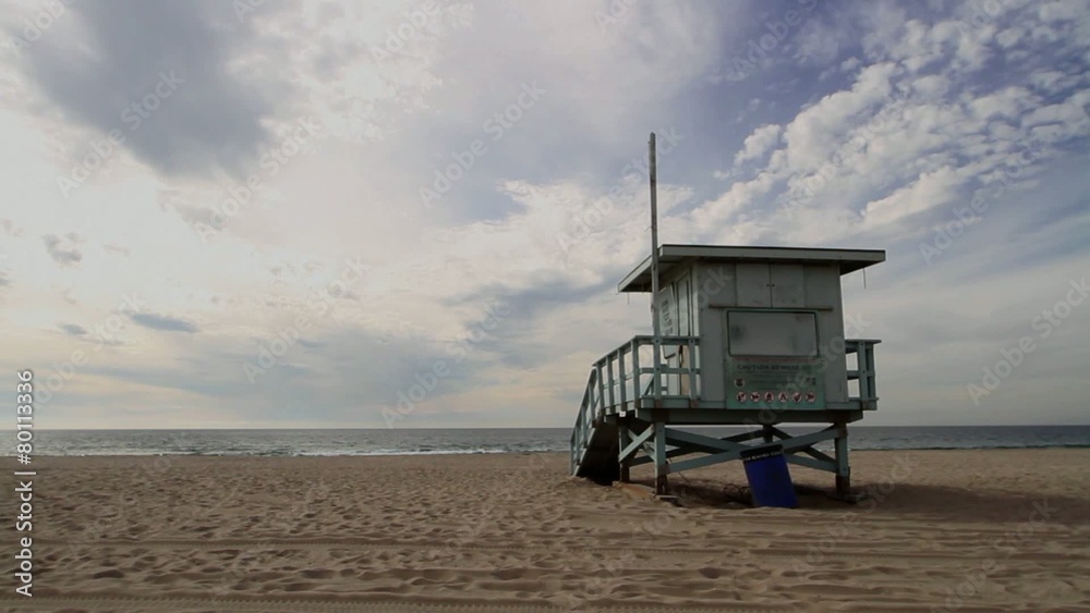 Empty beach with a lifeguard hut in California, USA, looking out towards the Pacific Ocean and a beautiful sky.