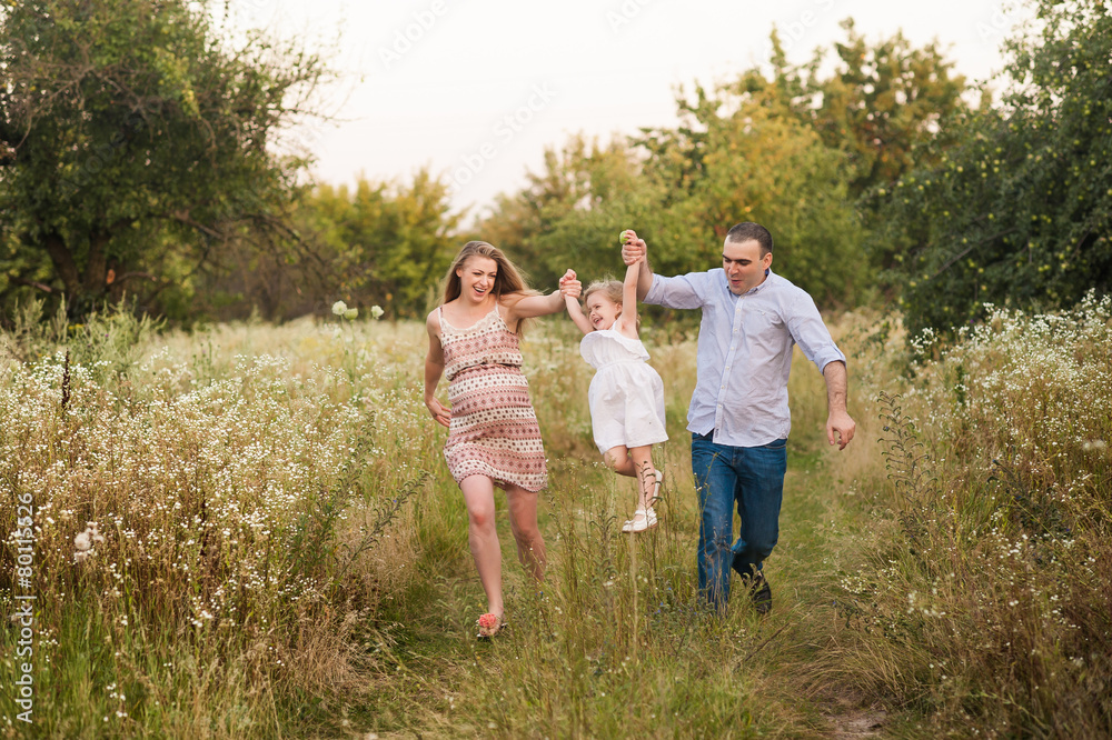 Girl jumpling over hand in hand with parents Girl jumpling over hand in hand with parents