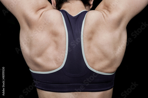 Woman training in a gym and showing her back muscles