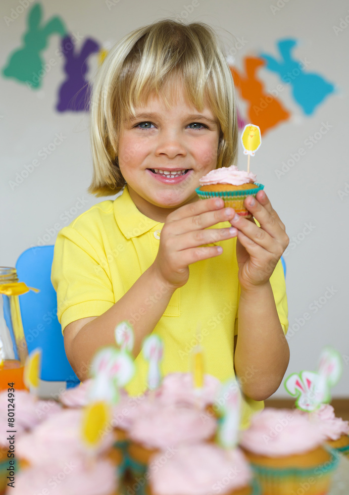 Fototapeta premium Smiling little boy with cupcakes in Easter scene