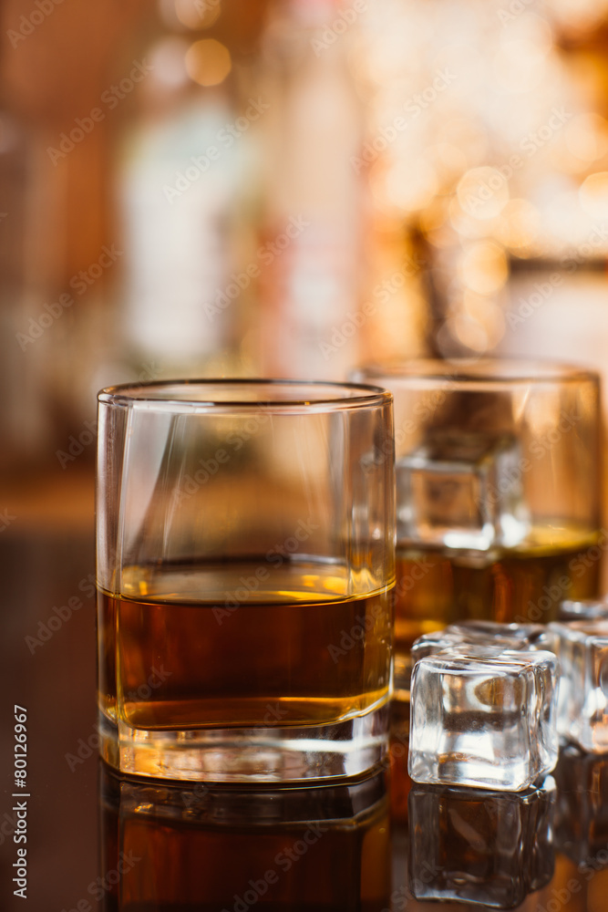 whiskey glass with ice and warm light on black table