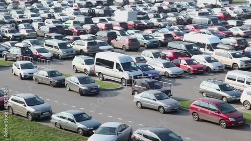 offroadster rides by path near parking with lot of vehicles  and people photo