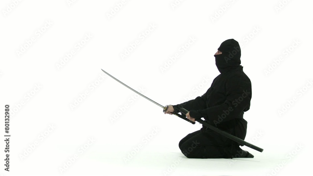 Seated assassin pulls out a long, curved sword and brandishes it, menacingly, then puts it away again. Profile shot against white background. Seated assassin pulls out a long, curved sword and brandishes it, menacingly, then puts it away again. Profile shot against white background.
