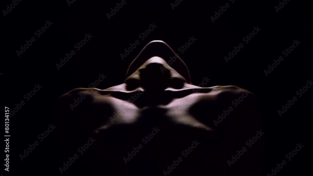 Lit torso, shoulders and chin of naked woman which leans back
