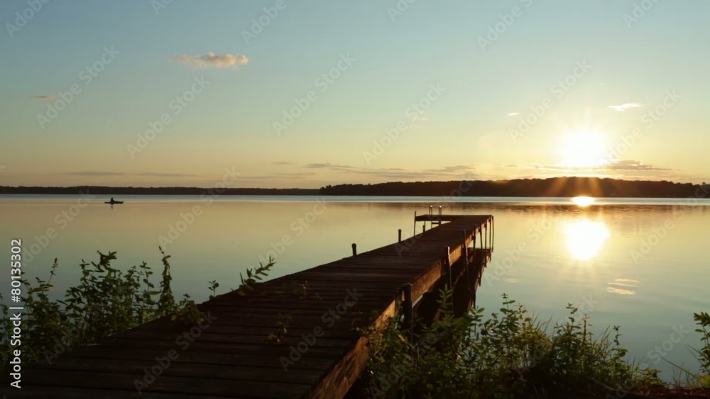 Sunrise over a small lake in Michigan, USA. Frame includes kayak, silhouetted against the water. Sunrise over a small lake in Michigan, USA. Frame includes kayak, silhouetted against the water.