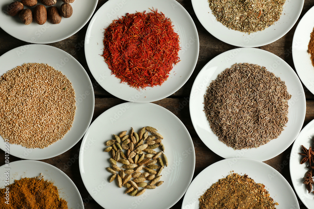 Different spices on plates, on old wooden table