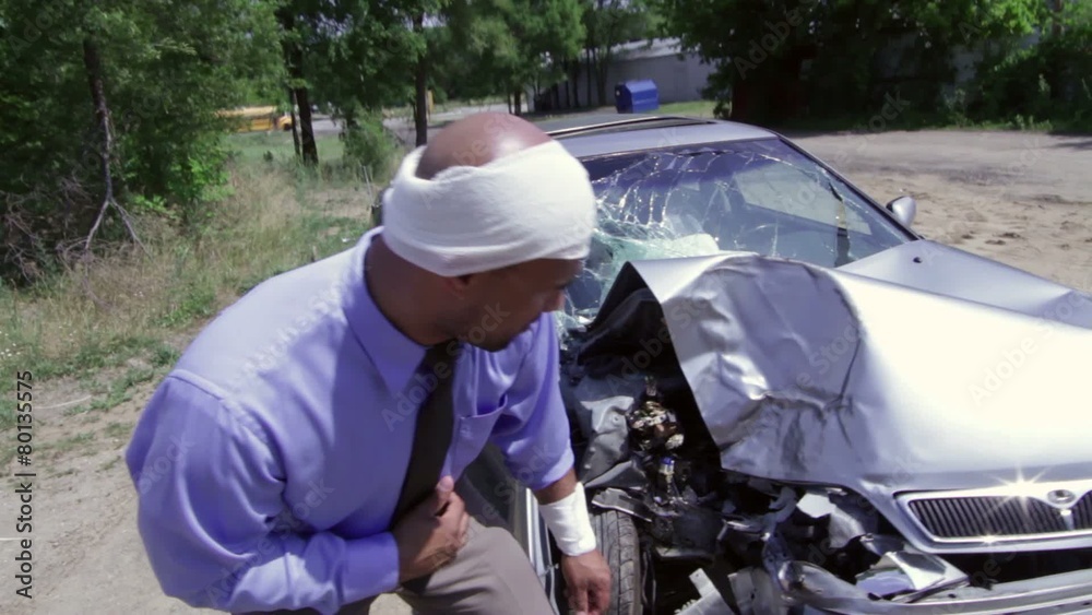 Bandaged driver stands by the wreckage of his car. No blood on bandage in this clip. Recorded with camera on jib arm. Bandaged driver stands by the wreckage of his car. No blood on bandage in this clip. Recorded with camera on jib arm.
