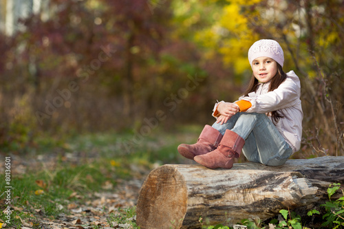 girl sitting on a log in the woods