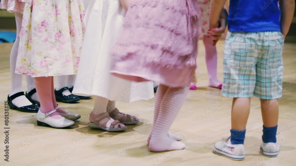 Girls in dresses and boy stand at parquet, only legs visible Girls in dresses and boy stand at parquet, only legs visible