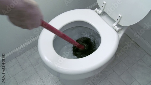 Using a plunger in an attempt to unclog a toilet.  Two clips with clean water in the bowl.