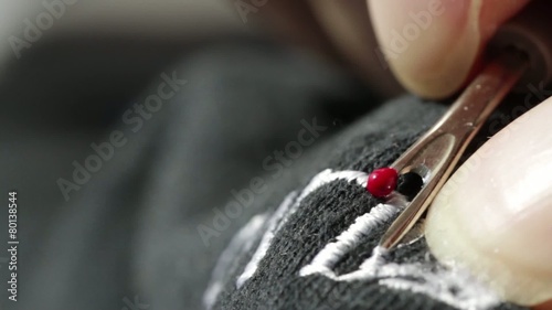 Unpicking the stitches from an embroidered design on black material.  Two clips shot with macro lens. photo