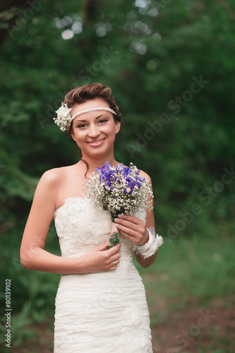 Beautiful young bride with a bouquet standing and smile photo