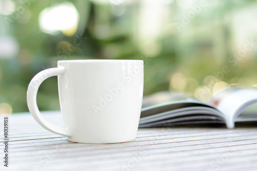 Coffee cup with book on wood table with blur bokeh background 
