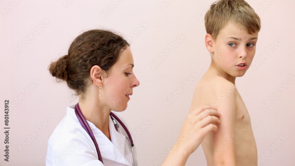 woman doctor in white dressing inspection back of boy in policlinic office woman doctor in white dressing inspection back of boy in policlinic office