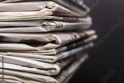 Journalism. Stack of newspapers on black background