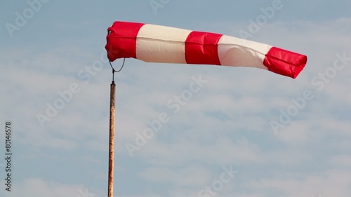 Wind sock flutters at background of sky with clouds photo