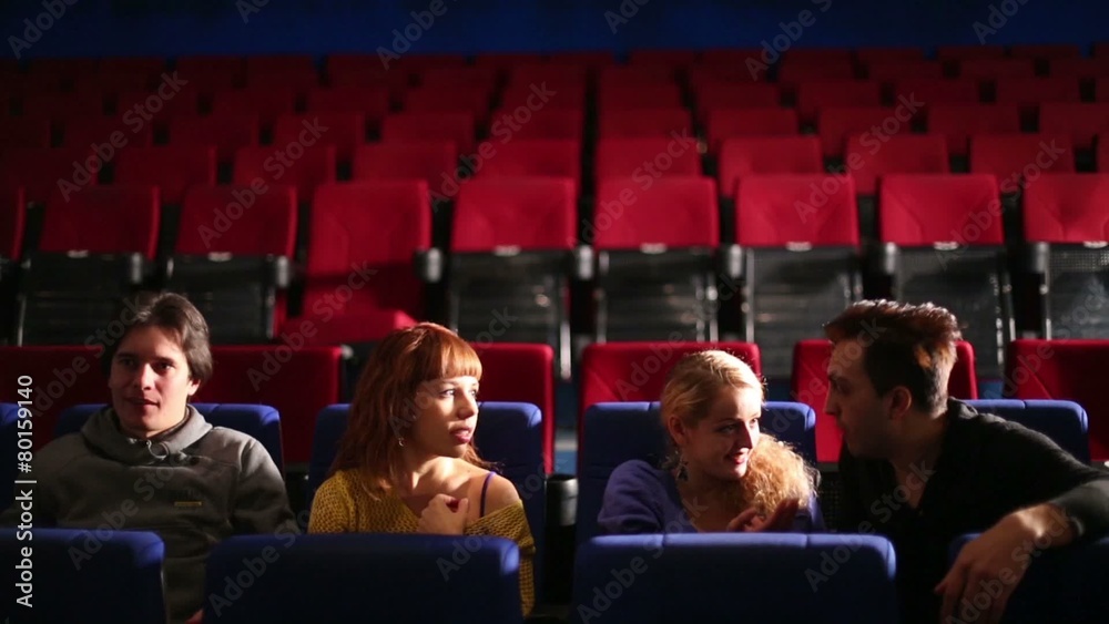 Four people sitting in dark hall cinema and discussing the film Four people sitting in dark hall cinema and discussing the film