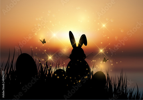 Easter bunny sat in grass against a sunset sky