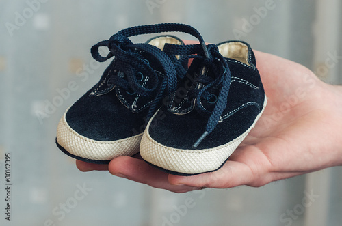 Baby shoes on parental hand
