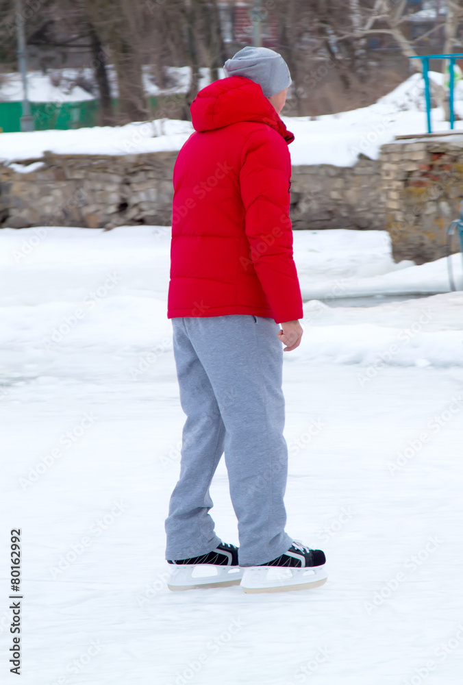 Boy in red jacket skates on ice