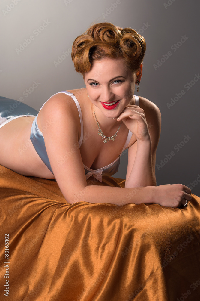 Fifties styled beautiful redheaded woman in satin lingerie Stock Photo