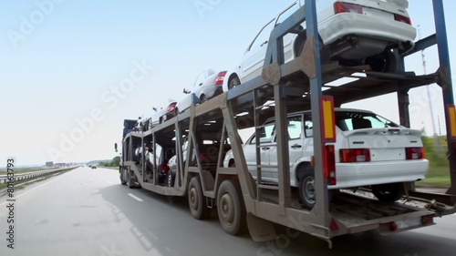 Carrier transports several cars by freeway at summer day