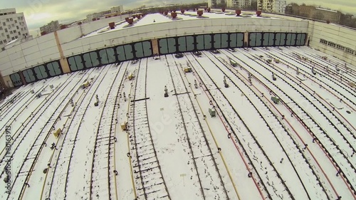 Many railroad tracks covered by snow near gates of train depot photo