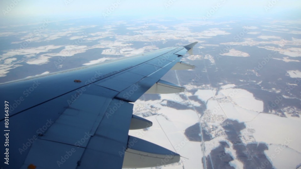 Wing of aircraft and landscape with fields and small towns
