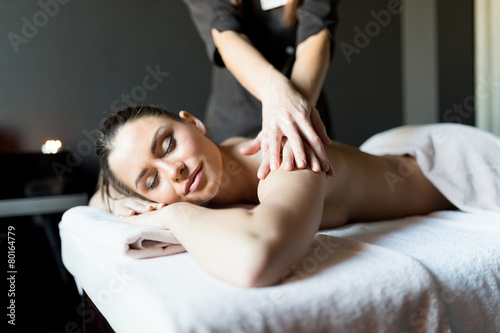 Beautiful, young lady having her shoulder and body massaged