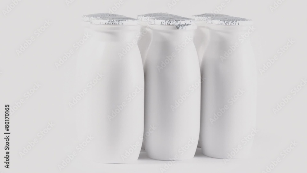 Six plastic bottles with foil cap of yogurt circling on table Six plastic bottles with foil cap of yogurt circling on table