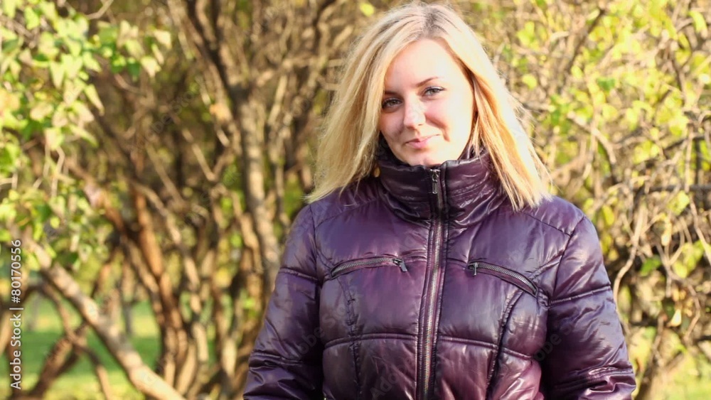 Young blonde woman looks and speaks in park at sunny autumn day Young blonde woman looks and speaks in park at sunny autumn day