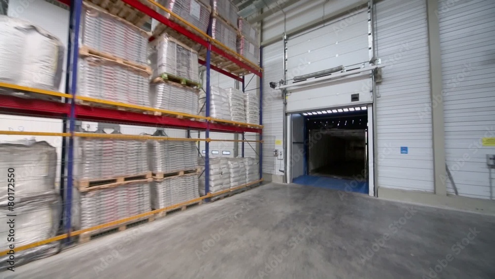 Goods lay on shelves in big warehouse with gates at factory Goods lay on shelves in big warehouse with gates at factory