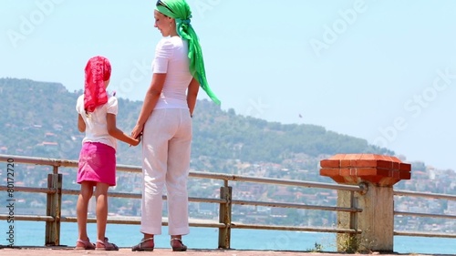 Mother and little daughter stand on bunder looking at bay