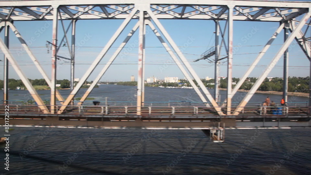railway bridge through river with workers on it and city behind railway bridge through river with workers on it and city behind