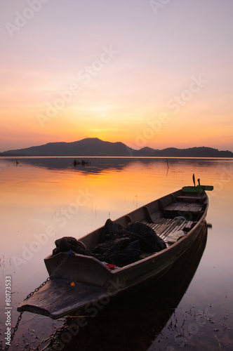Small fishing boat in lake at the sunset background.