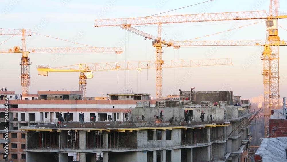 Lots of construction cranes and builders at construction site Lots of construction cranes and builders at construction site