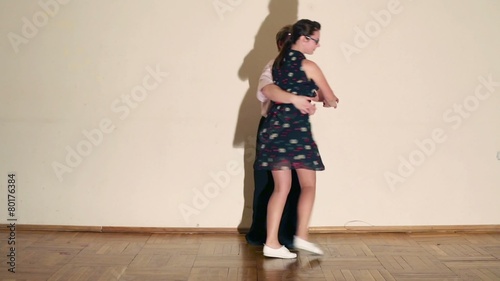 Girl and man in bow-tie dance boogie-woogie near wall photo