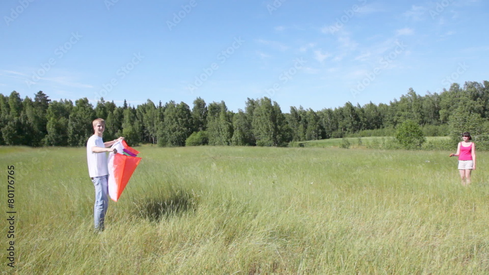 guy with girl fly together kite in field near wood guy with girl fly together kite in field near wood