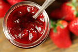 Jar of strawberry jam with berries on table close up