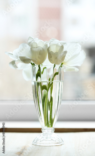 Beautiful tulips in vase on windowsill