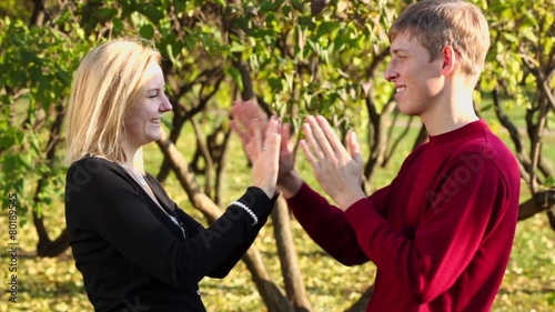 Young couple play pat a cake game and smiles in park at autumn photo