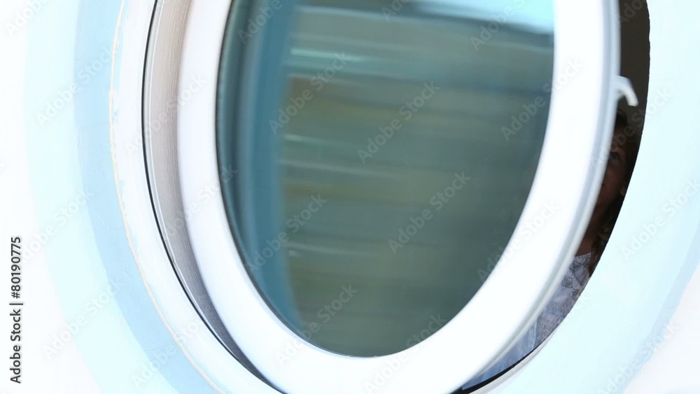 Smiling little girl in white dress closes and opens round window