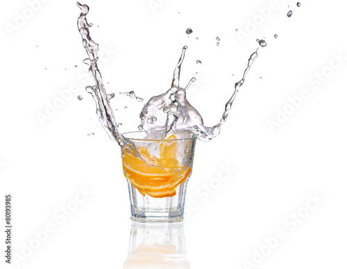 Orange or lemon slice fall in glass with water and make splash